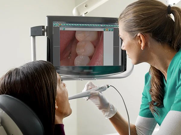 Dental team member showing a patient live intraoral camera footage of their teeth on a chairside screen